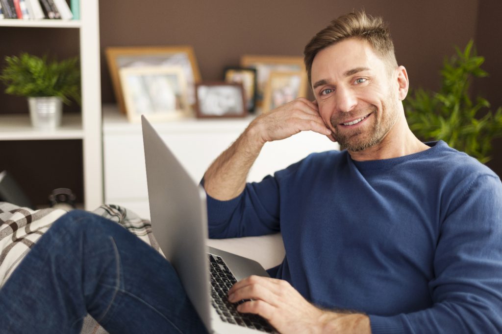 portrait of smiling man with laptop on sofa facebook 1024x683 1